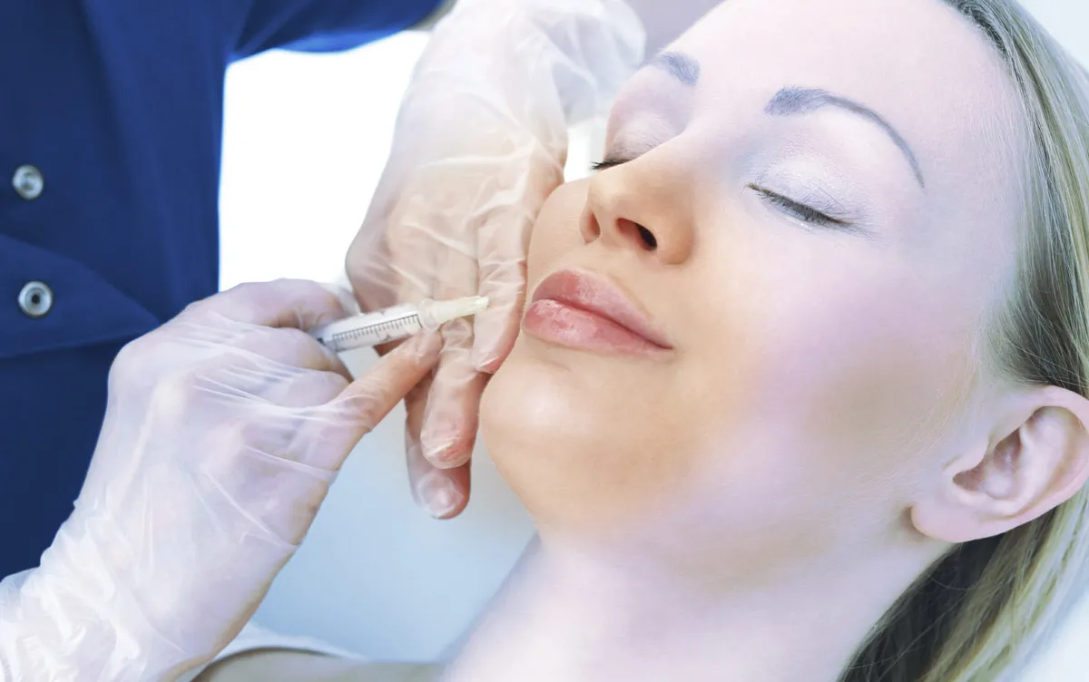 Eine Spritz ist bei den Lippen einer weiblichen Person angesetzt