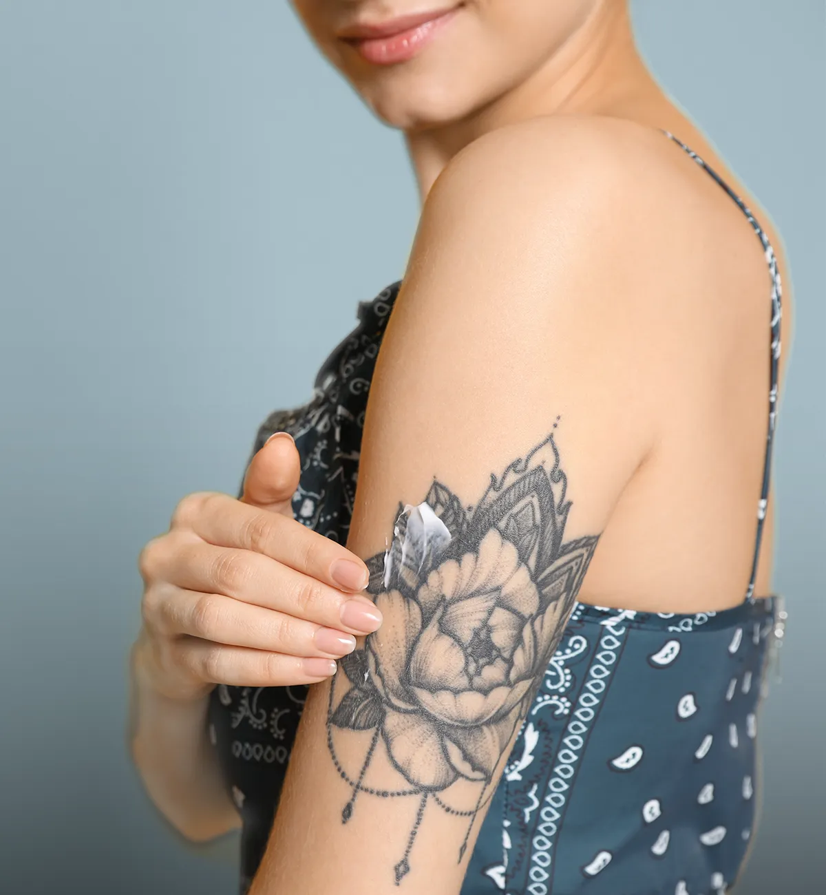 Eine weibliche Person reibt Creme auf einem Blumentattoo auf einem linken Oberarm